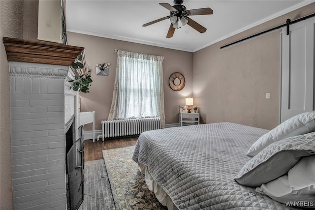 bedroom with radiator, wood-type flooring, ornamental molding, and a barn door