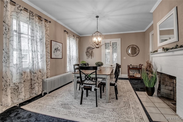 tiled dining area with ornamental molding, radiator, a notable chandelier, and a fireplace