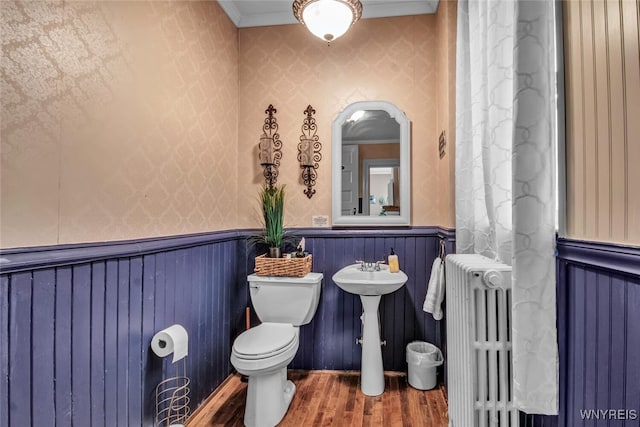 bathroom featuring hardwood / wood-style floors, radiator heating unit, ornamental molding, and toilet