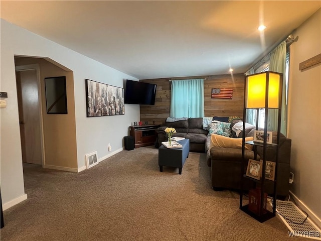 carpeted living room with wood walls