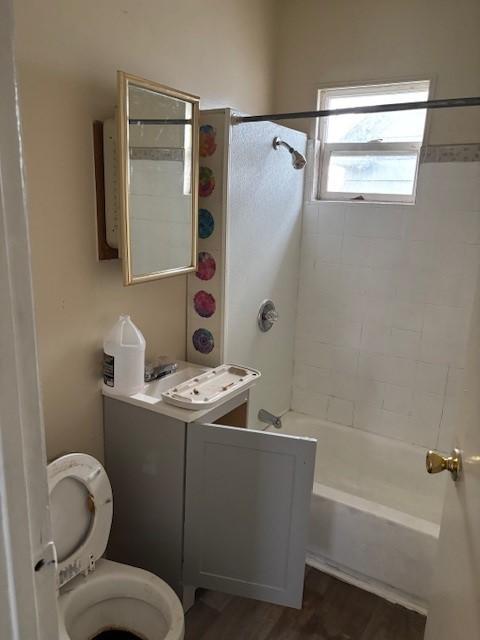 full bathroom with vanity, hardwood / wood-style floors, toilet, and tiled shower / bath