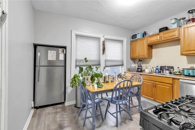 kitchen featuring appliances with stainless steel finishes, light hardwood / wood-style floors, sink, and decorative backsplash