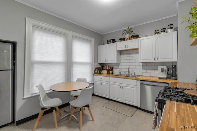 kitchen with stainless steel appliances, white cabinetry, sink, and wood counters