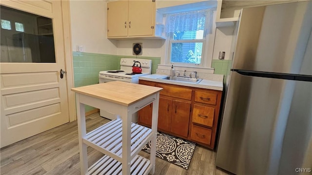 kitchen with sink, stainless steel fridge, white electric range oven, and light hardwood / wood-style flooring