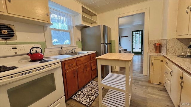 kitchen with sink, electric range, light wood-type flooring, and decorative backsplash