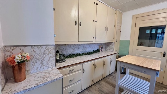 kitchen featuring tasteful backsplash, light hardwood / wood-style flooring, and white cabinets