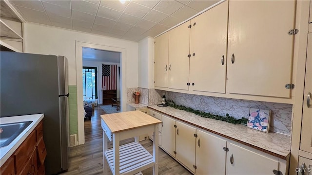 kitchen with stainless steel refrigerator, tasteful backsplash, sink, white cabinets, and light hardwood / wood-style floors