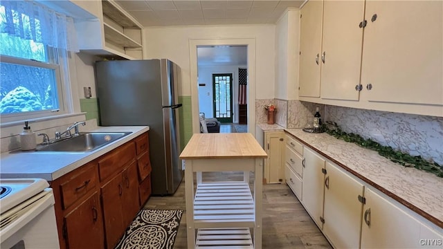 kitchen featuring sink, stainless steel fridge, backsplash, and light hardwood / wood-style floors