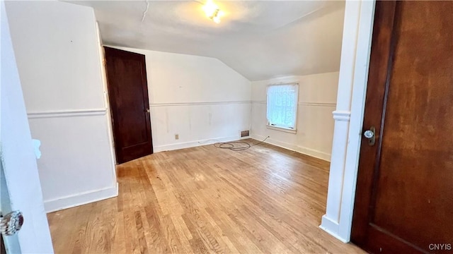 additional living space featuring lofted ceiling and light hardwood / wood-style flooring