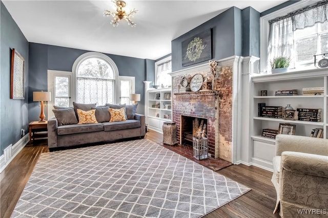 living room featuring dark hardwood / wood-style flooring, a fireplace, and an inviting chandelier