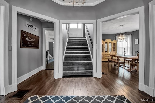 staircase with hardwood / wood-style floors and a chandelier