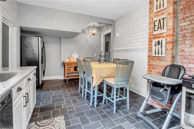 dining area with sink, a chandelier, and brick wall