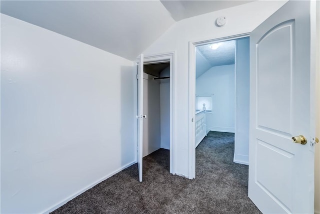 unfurnished bedroom featuring vaulted ceiling and dark colored carpet