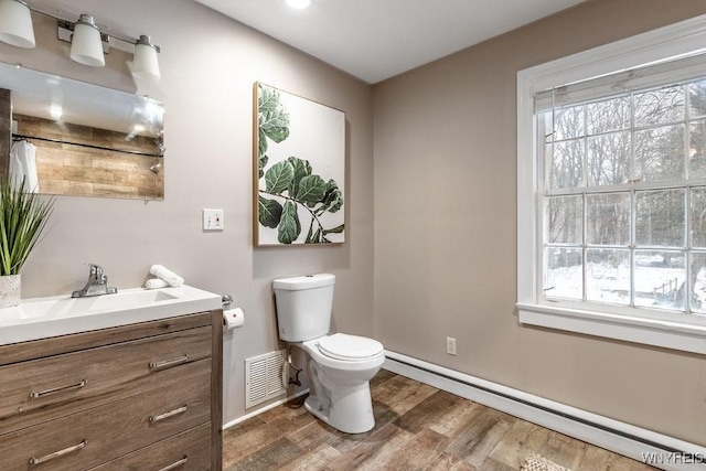 bathroom with a baseboard radiator, toilet, wood-type flooring, and plenty of natural light