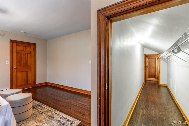 hallway with dark wood-type flooring and vaulted ceiling