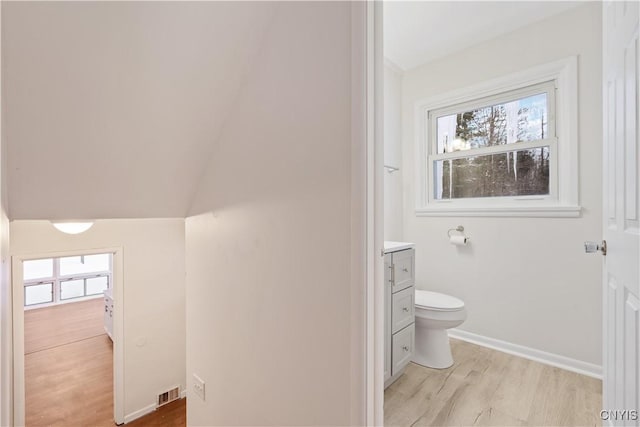 bathroom with toilet, wood finished floors, visible vents, vanity, and baseboards