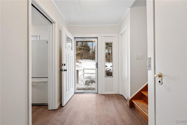 doorway with stairs, ornamental molding, a textured ceiling, and wood finished floors