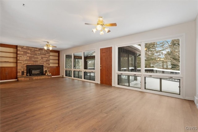 unfurnished living room with built in features, a ceiling fan, and wood finished floors