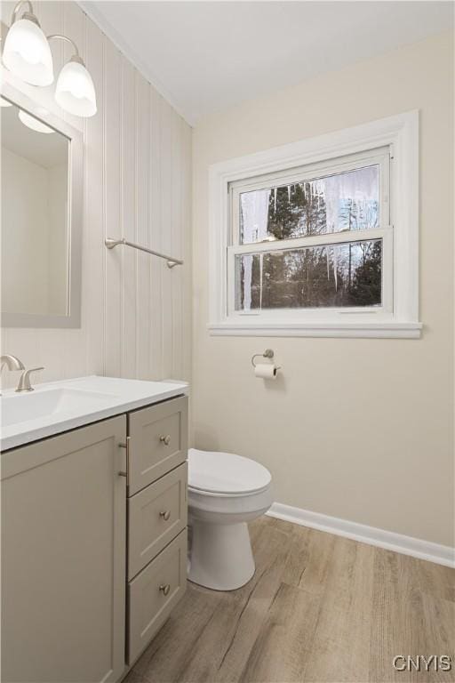 bathroom with baseboards, vanity, toilet, and wood finished floors