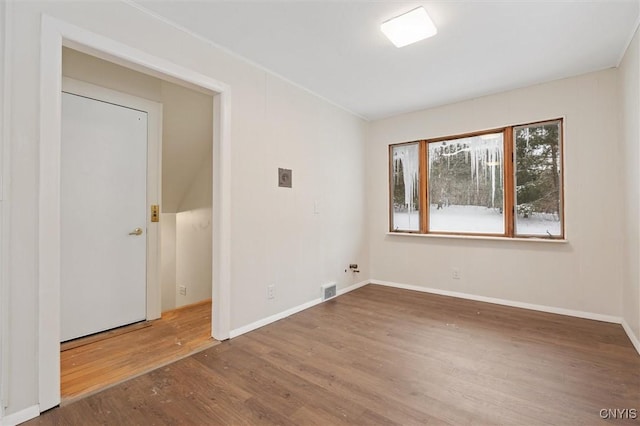 spare room with wood finished floors, visible vents, and baseboards