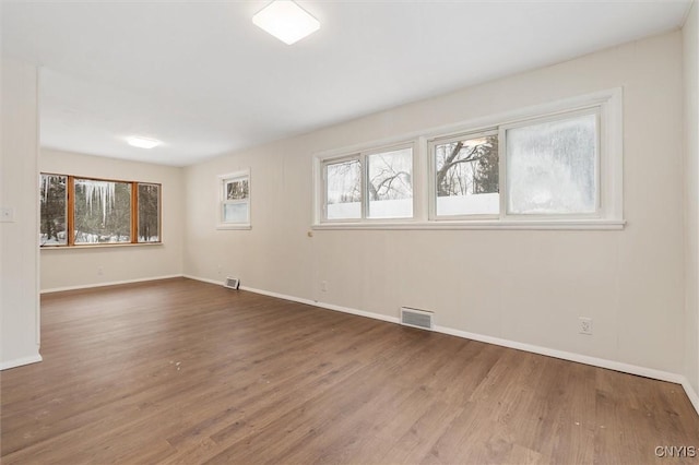 unfurnished room with baseboards, visible vents, and wood finished floors