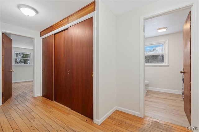 corridor with light wood-type flooring and baseboards