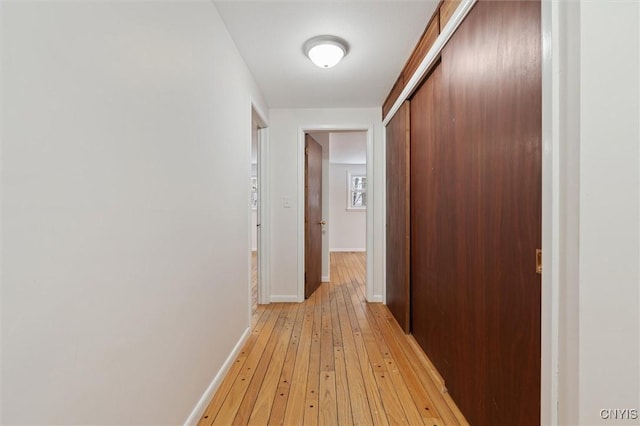 hallway with light wood-type flooring and baseboards