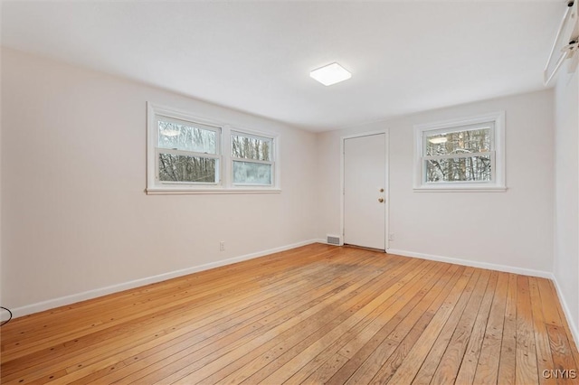 empty room featuring baseboards, plenty of natural light, and light wood-style floors