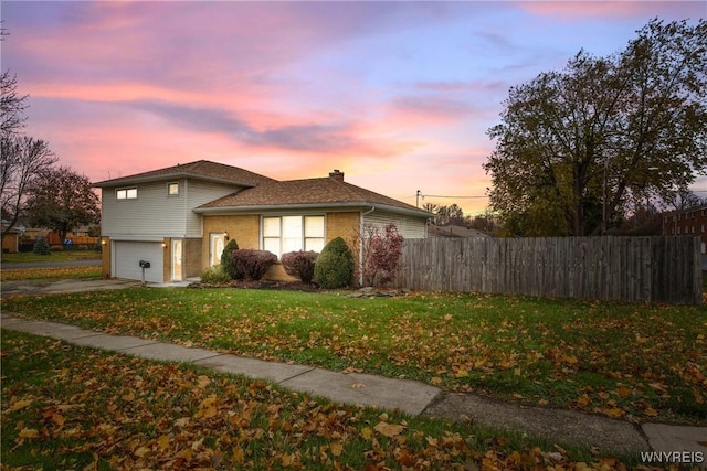 property exterior at dusk featuring a yard and a garage