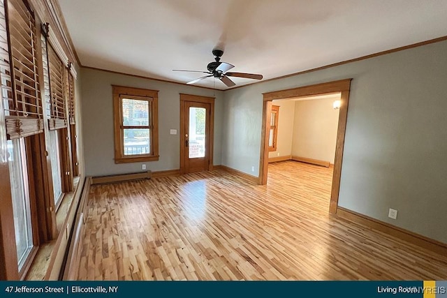 unfurnished living room with crown molding, ceiling fan, a baseboard heating unit, and light wood-type flooring