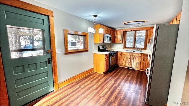 kitchen with dark wood-style floors, decorative light fixtures, stainless steel appliances, light countertops, and a chandelier