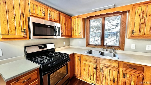 kitchen featuring brown cabinets, appliances with stainless steel finishes, light countertops, and a sink