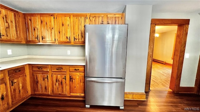 kitchen with brown cabinets, dark wood finished floors, a baseboard radiator, light countertops, and freestanding refrigerator