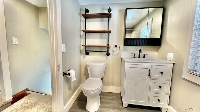 bathroom with toilet, baseboards, and vanity