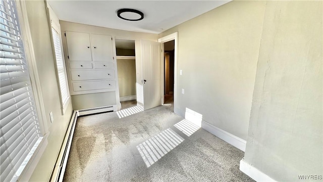 unfurnished bedroom with a baseboard heating unit, carpet floors, a closet, and baseboards