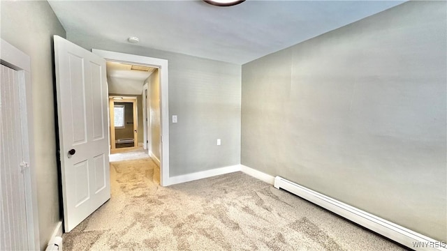 spare room with baseboards, baseboard heating, and light colored carpet