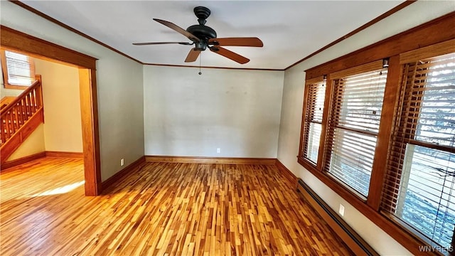 empty room with light wood-style flooring, baseboard heating, ornamental molding, baseboards, and stairs