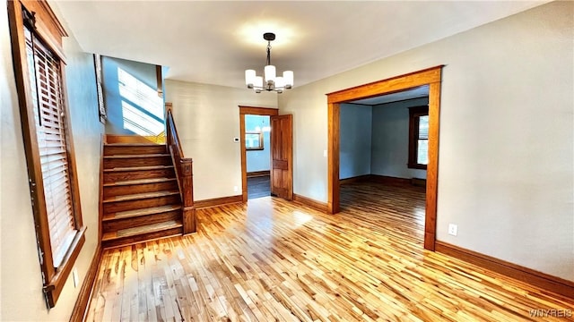 interior space with stairs, light wood-type flooring, baseboards, and an inviting chandelier