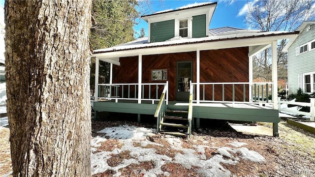 back of house with covered porch and metal roof