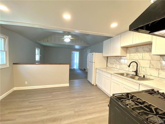 kitchen featuring sink, white refrigerator, white cabinets, gas range oven, and exhaust hood