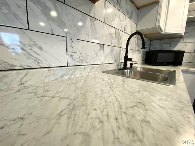 kitchen with sink, white cabinets, and backsplash