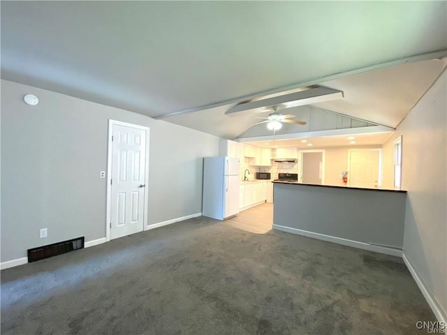 unfurnished living room with sink, carpet floors, lofted ceiling with beams, and ceiling fan