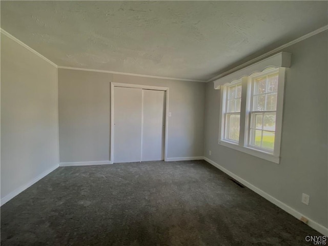 spare room with ornamental molding, a textured ceiling, and dark colored carpet