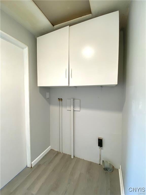 laundry room with light hardwood / wood-style floors and cabinets