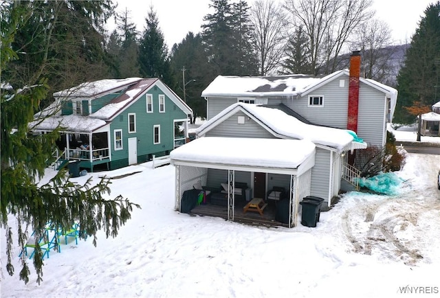 snow covered rear of property with a porch