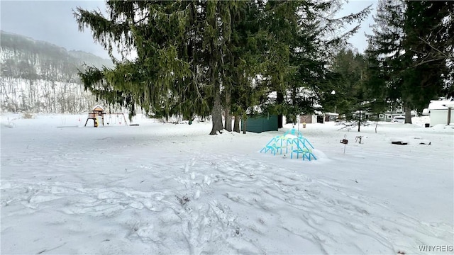 yard layered in snow featuring a playground