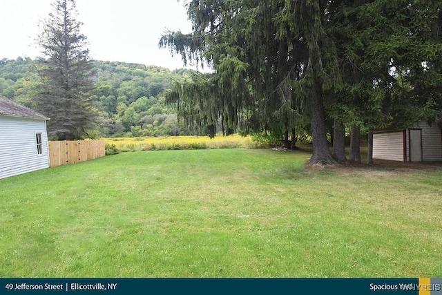 view of yard featuring fence and a wooded view