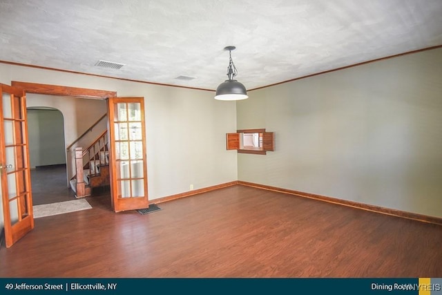 empty room with ornamental molding, a textured ceiling, dark hardwood / wood-style flooring, and french doors