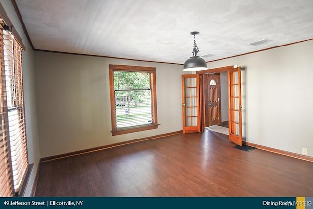 empty room with ornamental molding, visible vents, baseboards, and wood finished floors