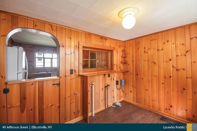 interior space with dark wood-type flooring, sink, and wooden walls